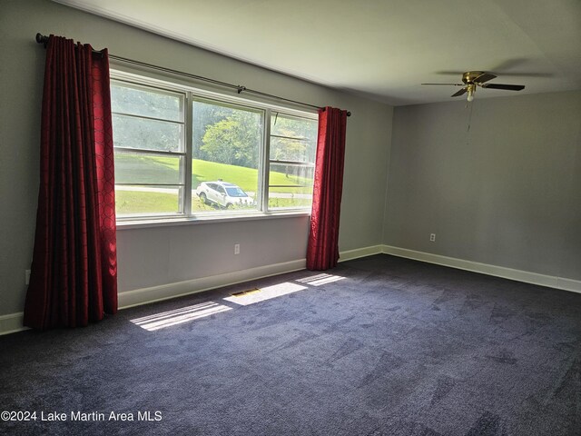 spare room featuring ceiling fan and dark carpet