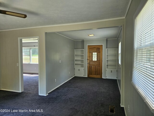 carpeted foyer with a textured ceiling, ceiling fan, and crown molding