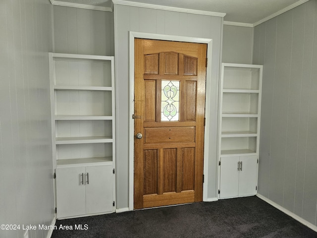 entrance foyer with wooden walls, dark carpet, and ornamental molding