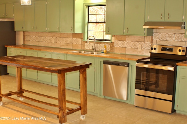 kitchen with appliances with stainless steel finishes, tasteful backsplash, sink, light tile patterned floors, and green cabinets