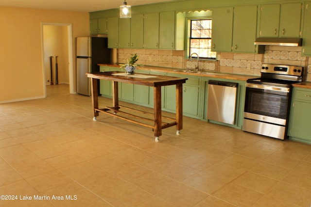 kitchen featuring butcher block counters, sink, green cabinets, light tile patterned floors, and appliances with stainless steel finishes