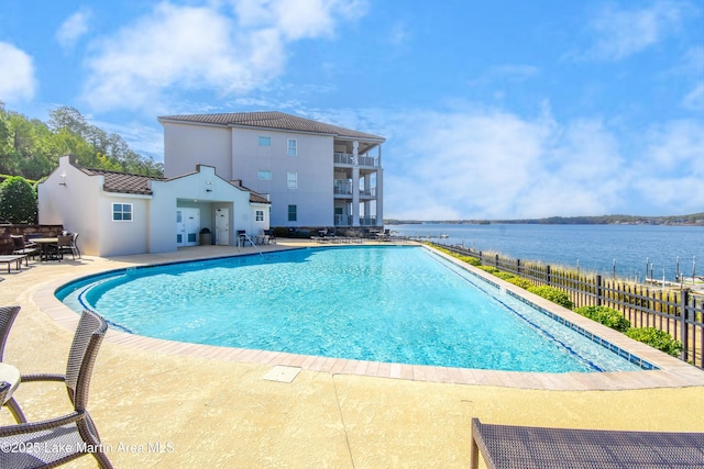 community pool featuring a water view, a patio area, and fence