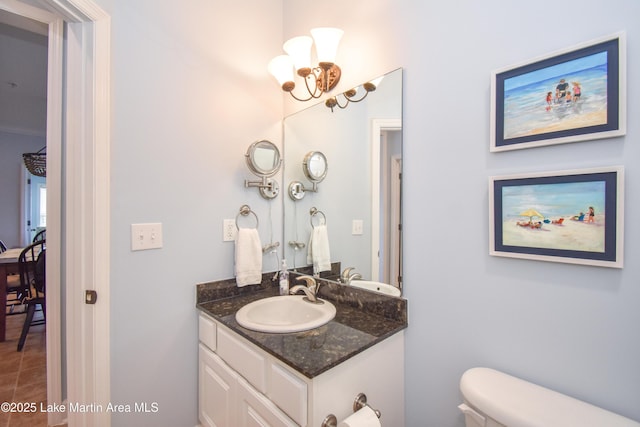 bathroom featuring vanity, toilet, and an inviting chandelier