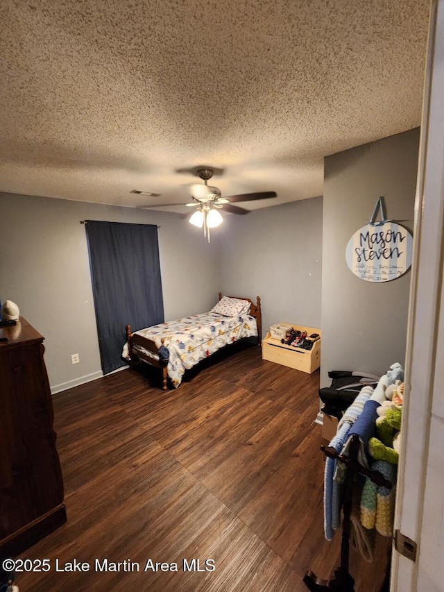 bedroom featuring ceiling fan, dark wood-type flooring, and a textured ceiling