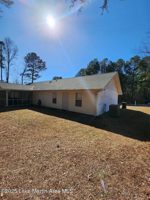 view of property exterior featuring central AC unit, a sunroom, and a lawn