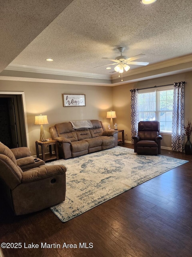 living room featuring crown molding, ceiling fan, a tray ceiling, and dark hardwood / wood-style flooring