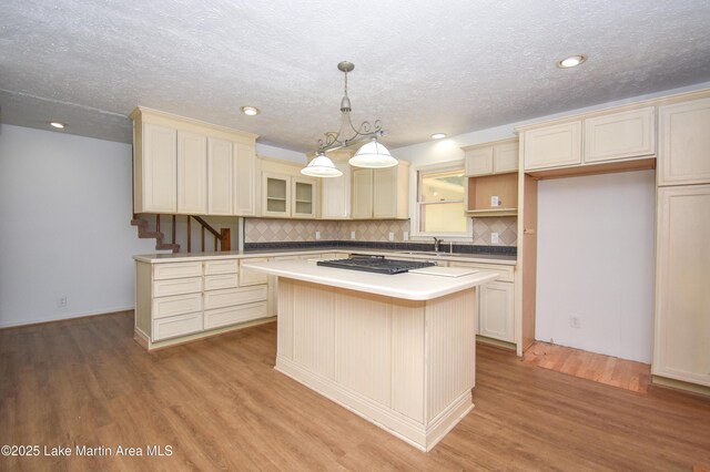 485 Ridgeview Dr, Alexander City, AL 35010 - kitchen featuring light wood-style flooring, a center island, decorative backsplash, glass insert cabinets, and cream cabinets