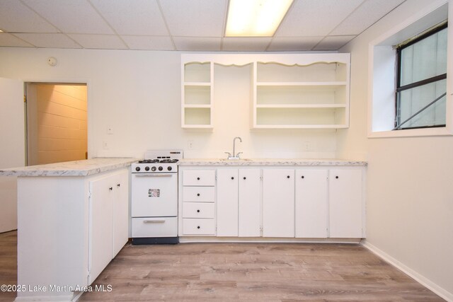 485 Ridgeview Dr, Alexander City, AL 35010 - kitchen with white range with gas stovetop, a peninsula, light wood-style floors, a drop ceiling, and white cabinetry