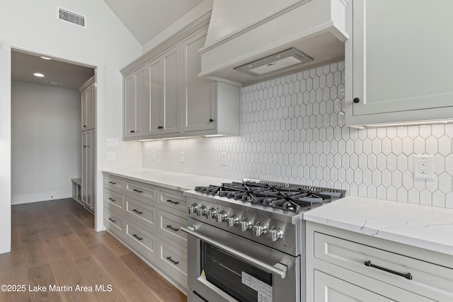 kitchen featuring vaulted ceiling, premium range hood, high end stainless steel range oven, backsplash, and dark wood-style floors