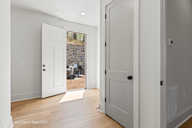 hall with baseboards, visible vents, and light wood-style flooring