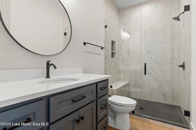 full bathroom with toilet, vanity, a stall shower, and wood finished floors