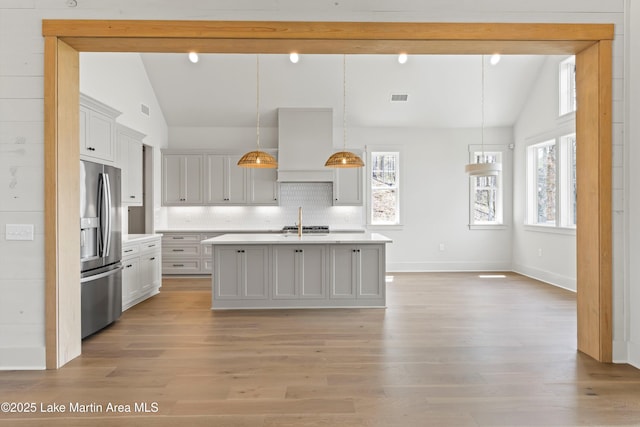 kitchen with light countertops, lofted ceiling with beams, stainless steel fridge with ice dispenser, a sink, and visible vents