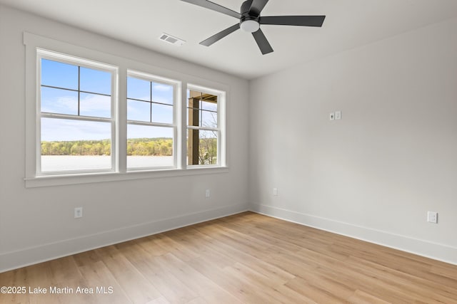empty room featuring baseboards, visible vents, ceiling fan, and light wood-style flooring
