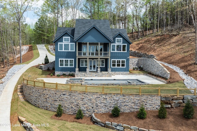 back of house featuring a balcony, french doors, board and batten siding, and fence private yard