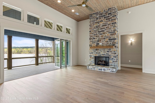 unfurnished living room featuring a towering ceiling, wood finished floors, wooden ceiling, and ceiling fan