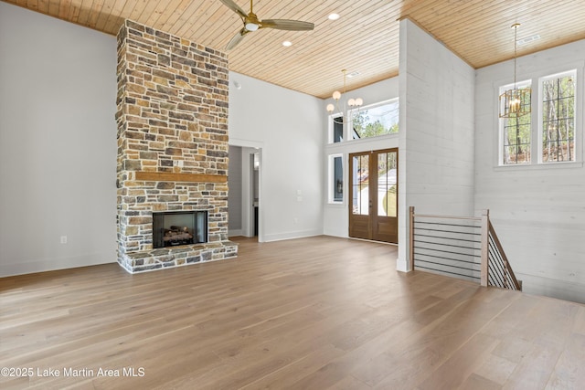 unfurnished living room with a wealth of natural light, wood finished floors, wooden ceiling, and ceiling fan with notable chandelier