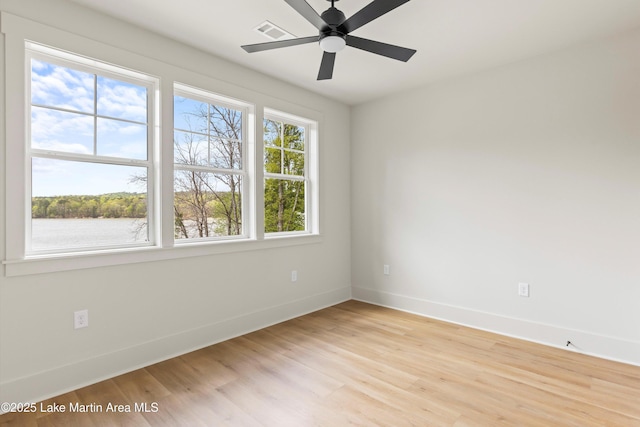 spare room featuring baseboards, a ceiling fan, visible vents, and light wood-type flooring