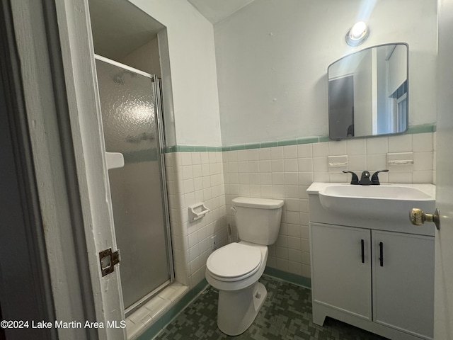 bathroom featuring vanity, a shower with door, toilet, and tile walls