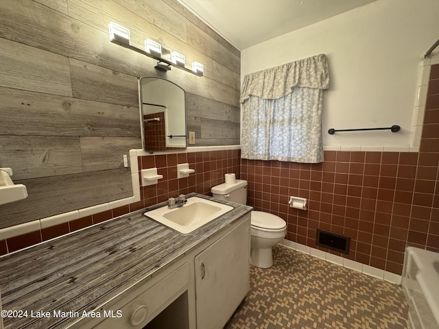 bathroom featuring vanity, toilet, and tile walls