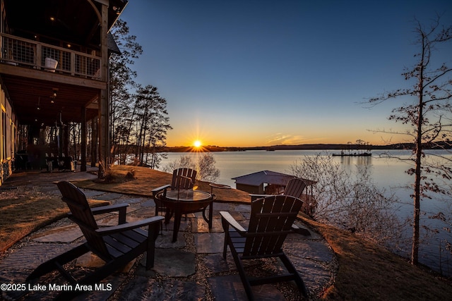 patio terrace at dusk with a water view and an outdoor fire pit