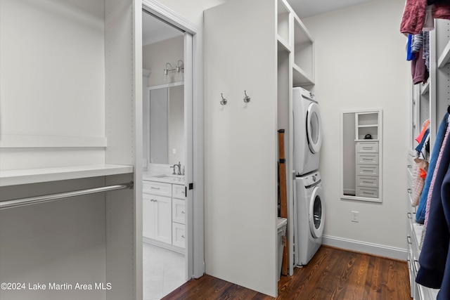 laundry room with sink, stacked washer / drying machine, and dark wood-type flooring