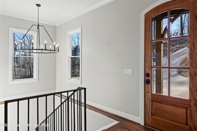 entryway with crown molding, dark hardwood / wood-style floors, and an inviting chandelier