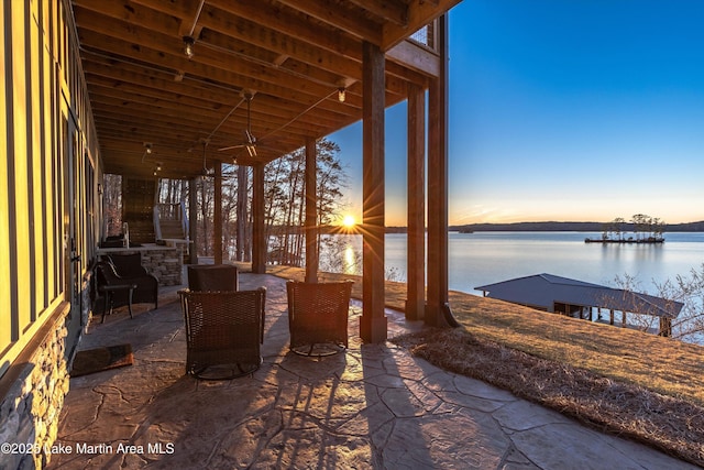 patio terrace at dusk with a water view and ceiling fan