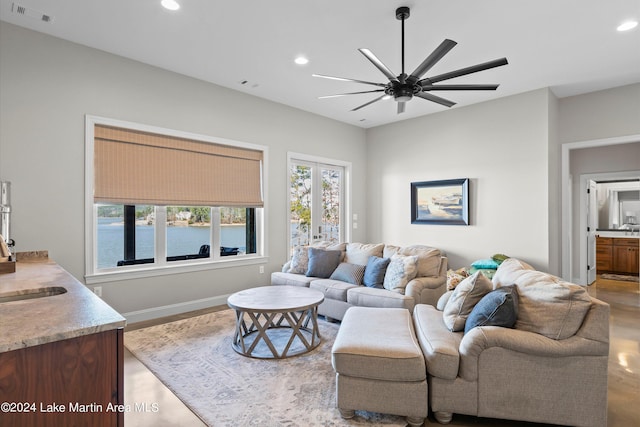 living room with ceiling fan, a water view, and wood-type flooring