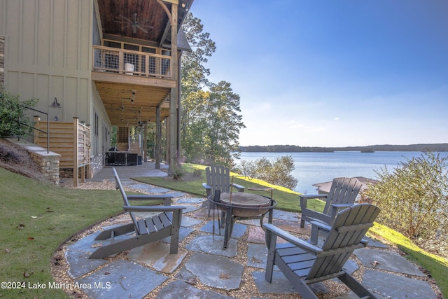 view of patio with a water view, an outdoor fire pit, a balcony, and ceiling fan