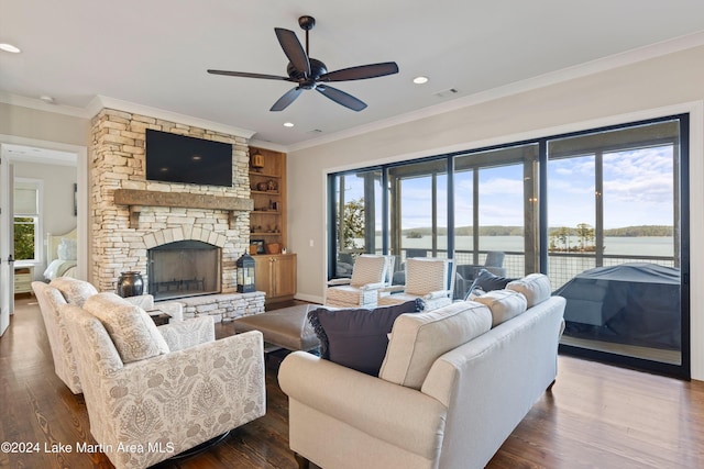 living room featuring ceiling fan, ornamental molding, a stone fireplace, and dark hardwood / wood-style floors