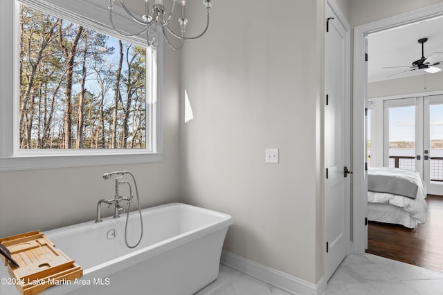 bathroom featuring a bathing tub and ceiling fan with notable chandelier