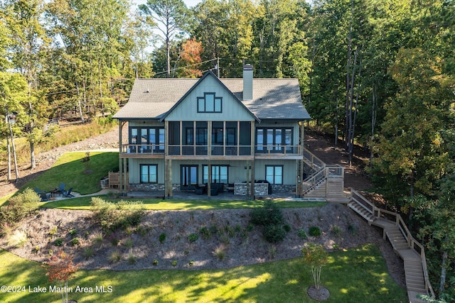 back of house featuring a sunroom, a lawn, an outdoor hangout area, a wooden deck, and a patio area