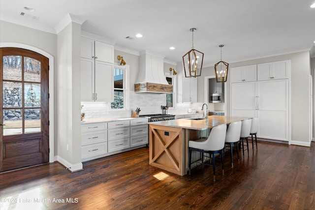 kitchen with custom range hood, a center island with sink, white cabinetry, and dark hardwood / wood-style floors