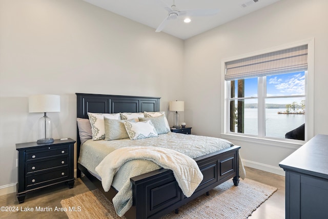 bedroom featuring ceiling fan and a water view