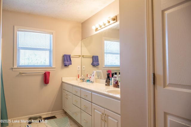 bathroom featuring vanity, plenty of natural light, tile patterned floors, and a textured ceiling