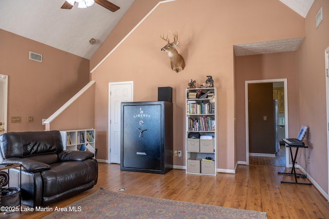 living room featuring high vaulted ceiling, ceiling fan, and light wood-type flooring