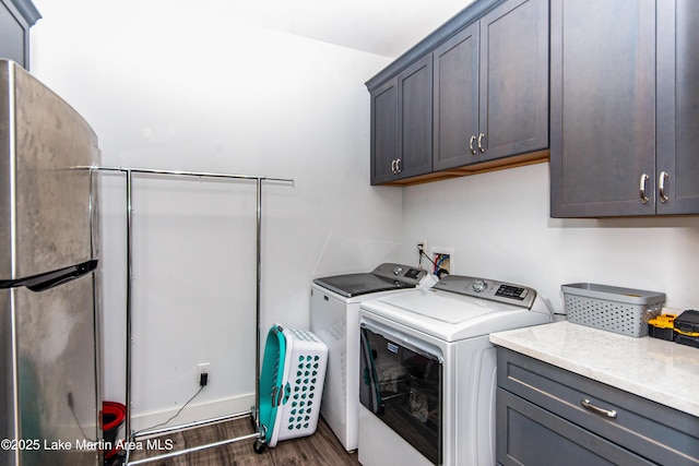 clothes washing area with dark hardwood / wood-style flooring, washer and clothes dryer, and cabinets