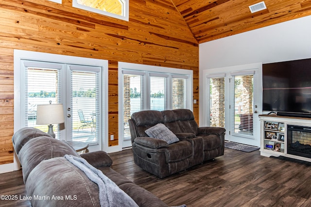 living room with dark hardwood / wood-style floors, high vaulted ceiling, and wood walls