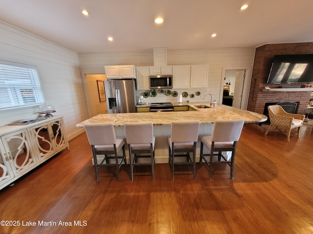 kitchen featuring sink, appliances with stainless steel finishes, a kitchen breakfast bar, a large island, and white cabinets