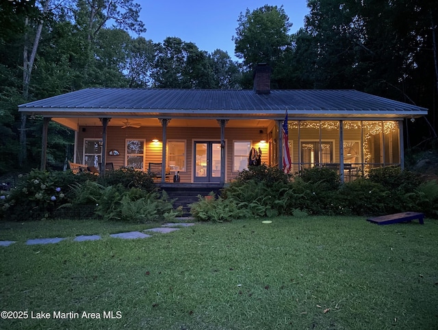 back house at dusk with a porch, a yard, and ceiling fan