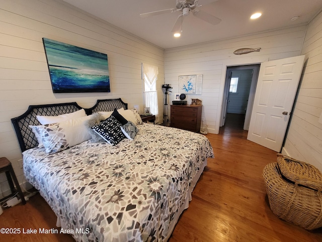 bedroom with ceiling fan, wooden walls, and hardwood / wood-style floors