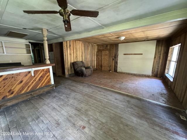 interior space with wooden walls, dark hardwood / wood-style flooring, and ceiling fan