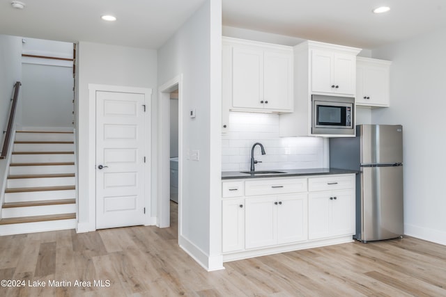 kitchen with white cabinets, appliances with stainless steel finishes, light hardwood / wood-style floors, and sink