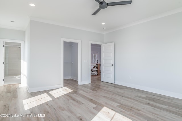 unfurnished bedroom featuring a walk in closet, ceiling fan, a closet, and light wood-type flooring