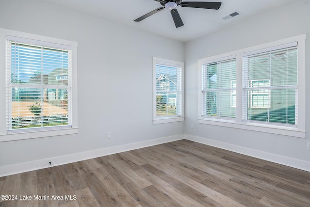 empty room featuring wood-type flooring, ceiling fan, and a healthy amount of sunlight