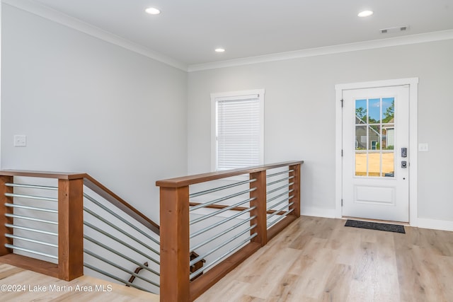 foyer with crown molding and light hardwood / wood-style floors