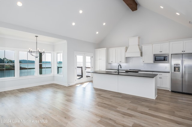 kitchen with appliances with stainless steel finishes, light wood-type flooring, a water view, and custom exhaust hood