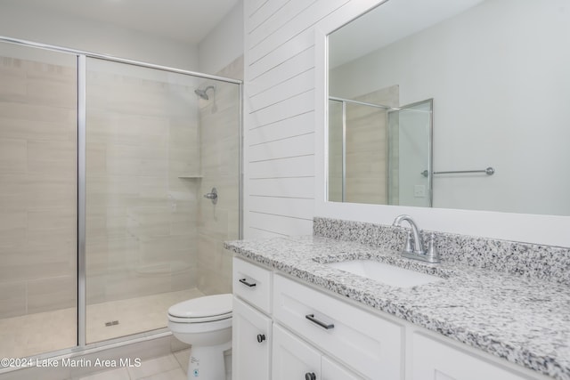 bathroom with tile patterned flooring, vanity, toilet, and a shower with shower door