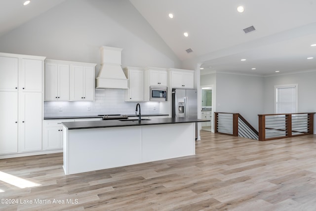 kitchen featuring white cabinetry, an island with sink, custom range hood, and appliances with stainless steel finishes