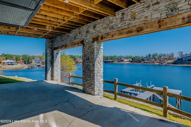 view of patio with a water view and a dock